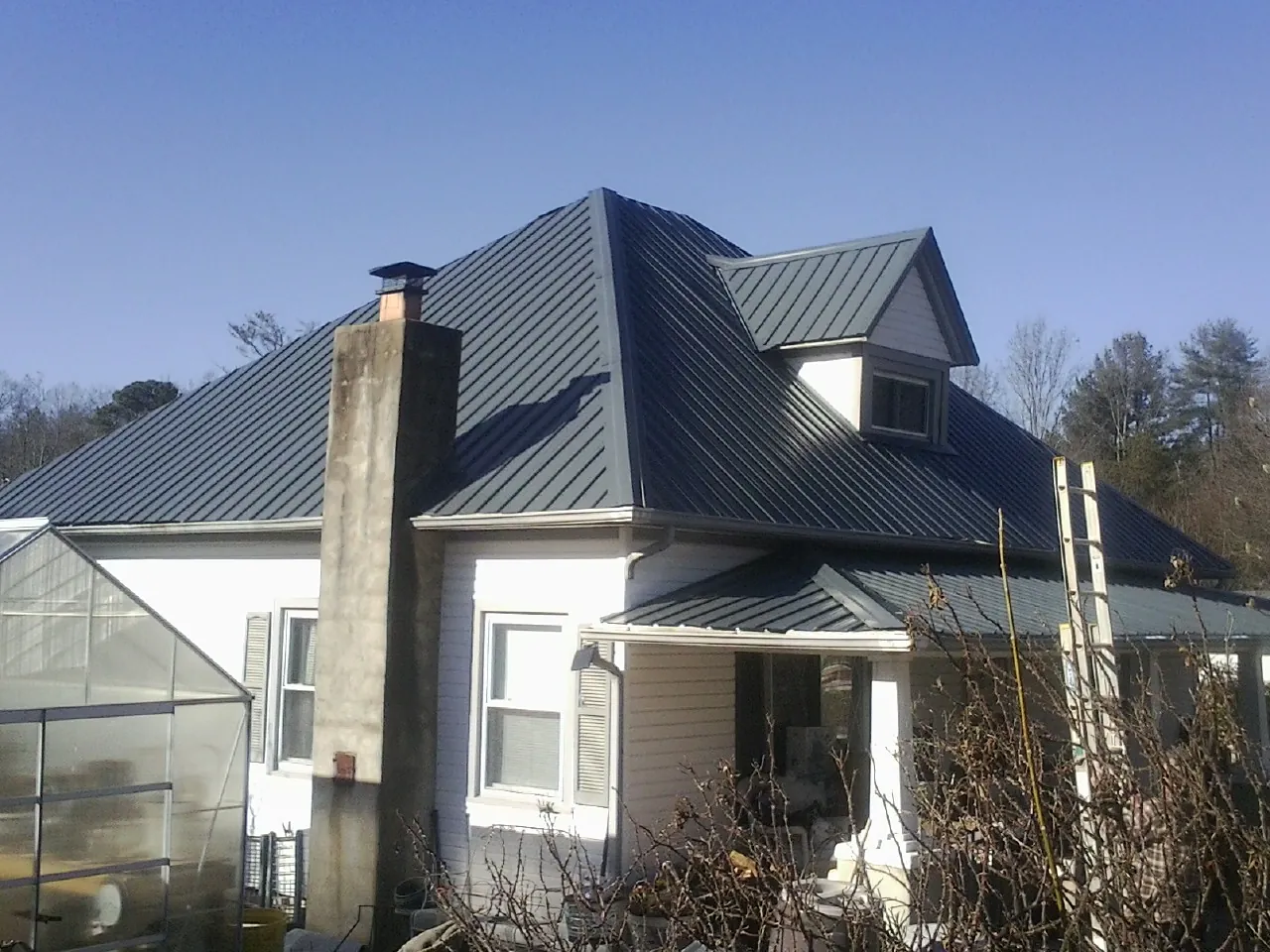 Dark blue standing seam metal roof on a white farmhouse with dormer — Slate & Tile Roof Repair by Roofing Brothers in Owensboro