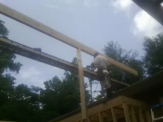 Carpenter setting a ridge beam over a new addition frame — Ice Dam Removal by Roofing Brothers in Owensboro