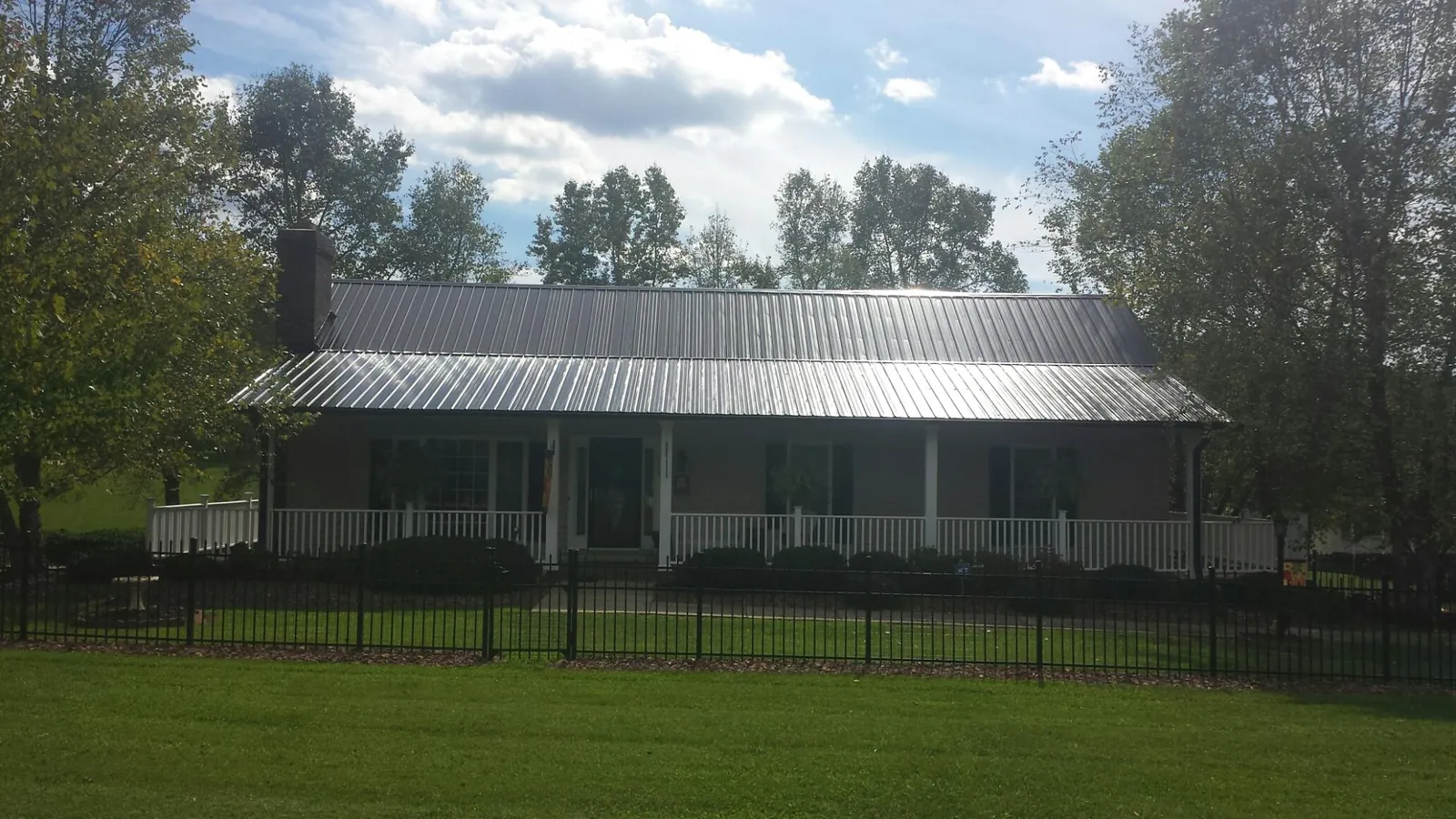 Gray metal roof on a brick ranch with a full width front porch — Gutter Guard Installation work by our crew in Owensboro
