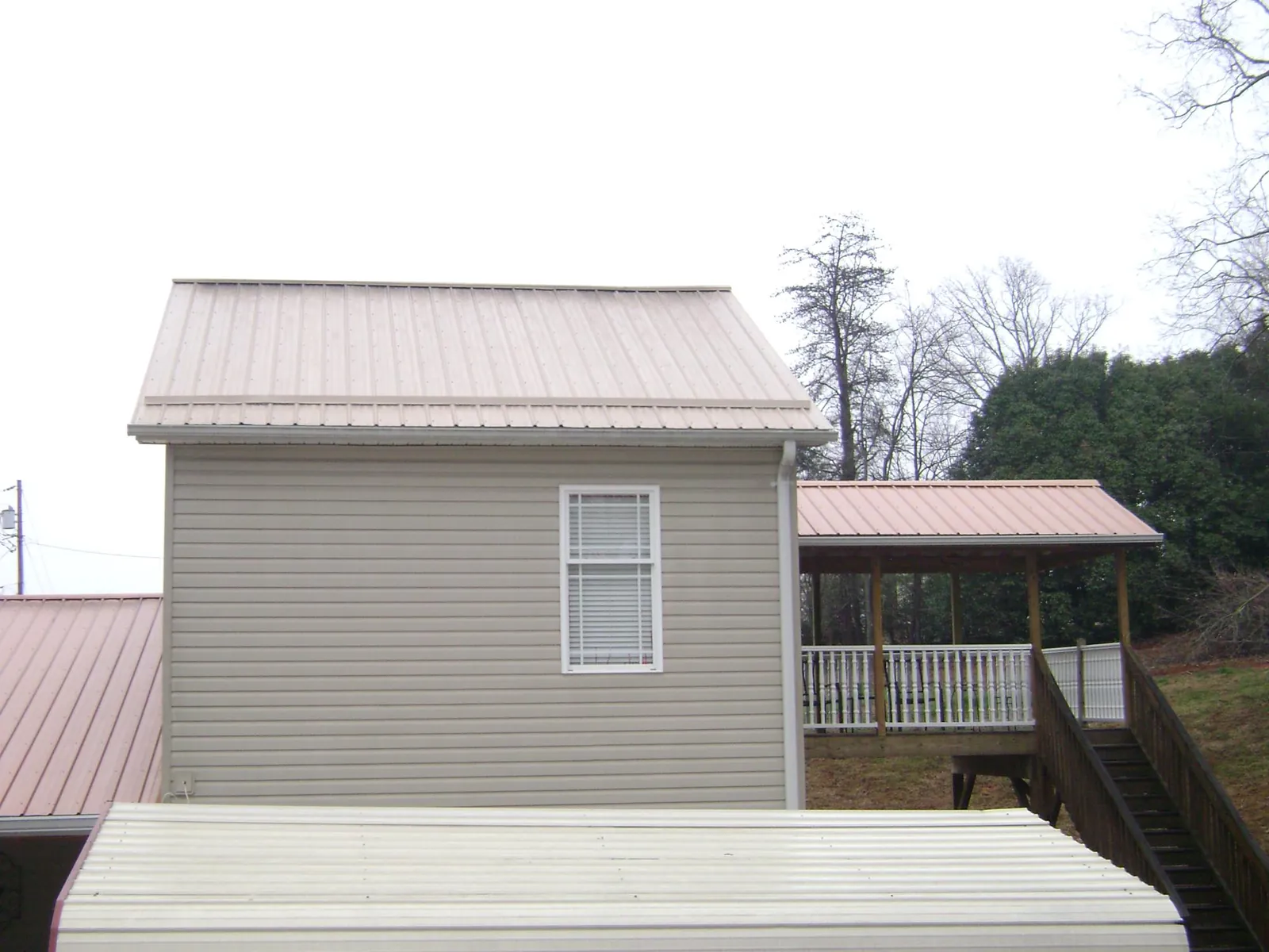 Tan metal roofs on a two story addition and attached porch, from a Roof Replacement job in Owensboro