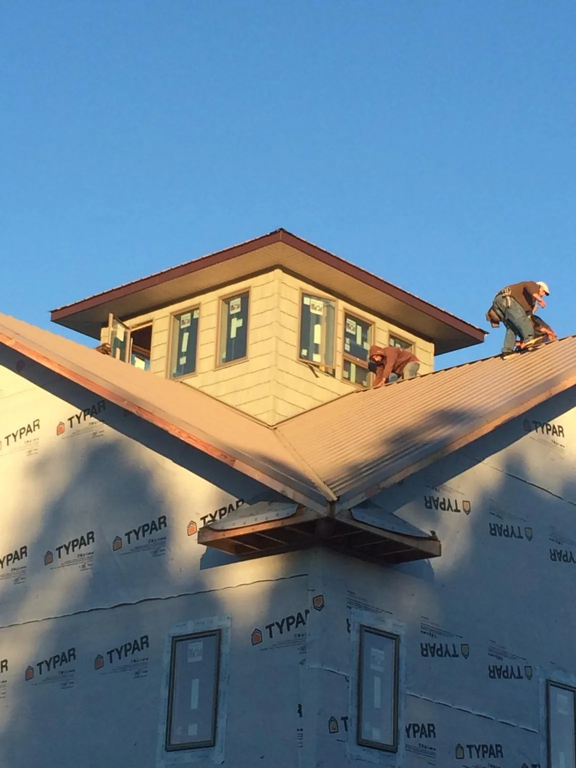 Roofers working around a rooftop cupola on a new metal roof at sunset — Roof Waterproofing in Owensboro by Roofing Brothers